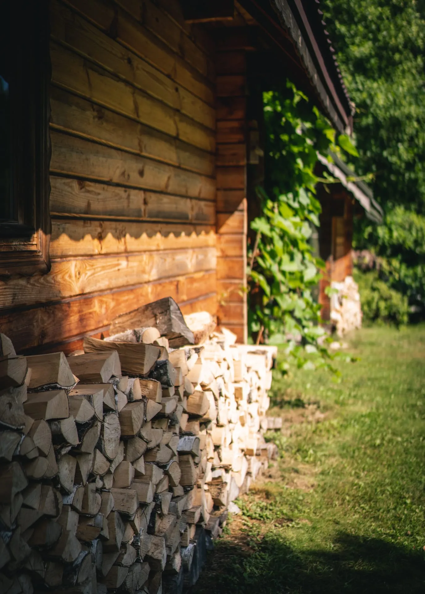 Stos opału pod ścianą domku w niskim, ciepłym świetle